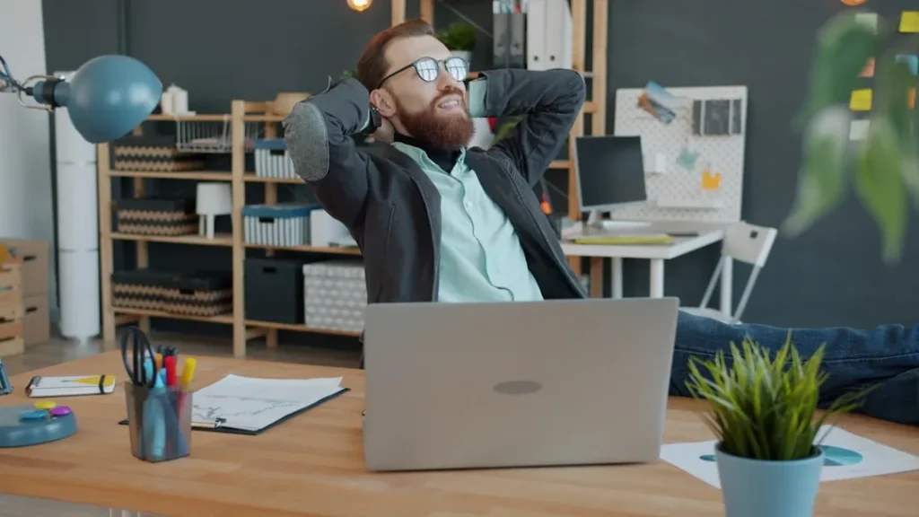 Man relaxing at his office desk with laptop.