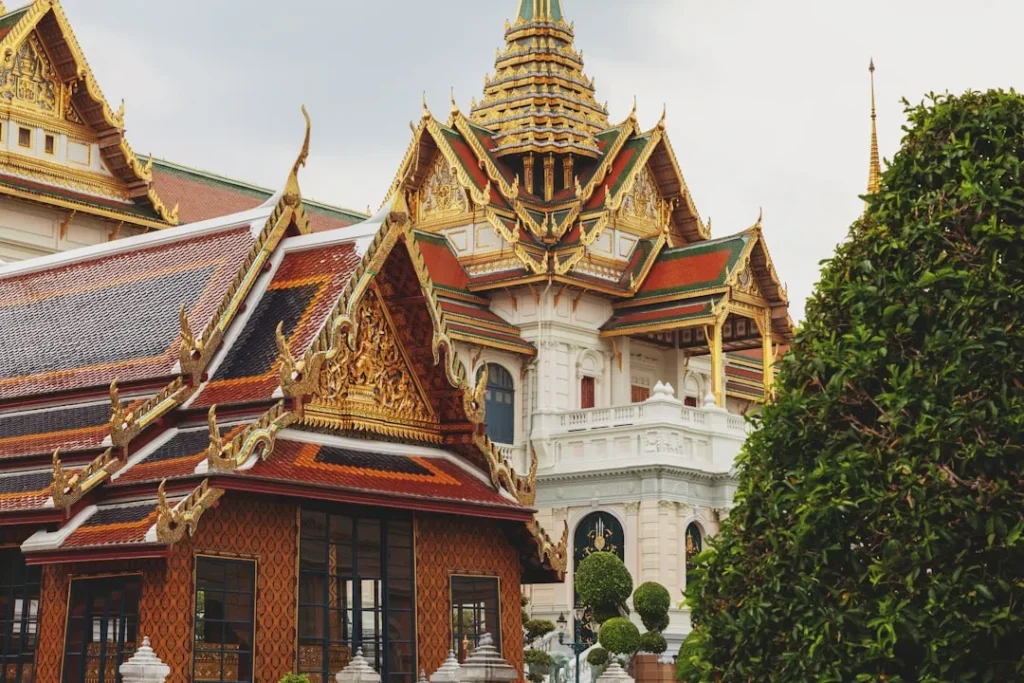 Ornate gilded temple buildings with lush green foliage.
